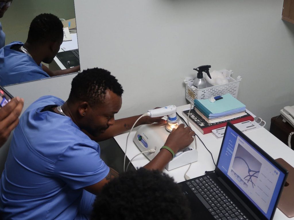 Certified trichologist Kagai John (KJ) inside his hair loss treatment clinic, doing scans before treatment begins